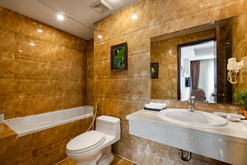 a bathroom with a toilet and a sink and a tub at First Eden Hotel - Hang Bun in Hanoi