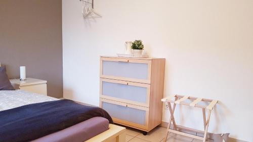 Un dormitorio con una cama y un tocador con una planta. en Ferienwohnung - Appartment Breivogel in Wörrstadt en Wörrstadt