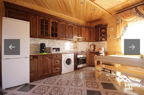 a kitchen with wooden cabinets and a white refrigerator at Садиба Надія in Sheshory