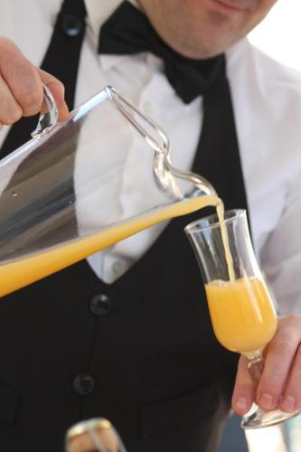 a man in a suit pouring a glass of orange juice at Hotel Lido in Vasto