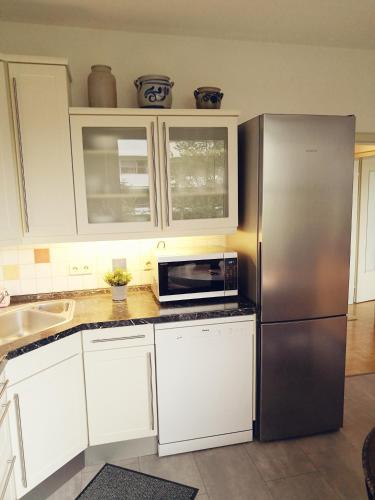 a kitchen with white cabinets and a stainless steel refrigerator at Ferienwohnung Confluentia in der Koblenzer Altstadt in Koblenz