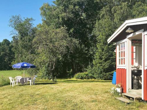 a house with a table and an umbrella in a yard at 6 person holiday home in VARA in Skår