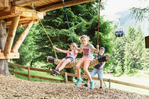 a group of children sitting on swings at a playground at Sporthotel Cristall in Fulpmes