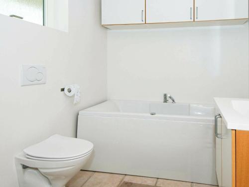a white bathroom with a toilet and a sink at 6 person holiday home in Knebel in Knebel