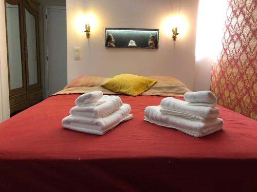 two stacks of towels sitting on a red bed at Love Nest Versailles - Unique Louis XIV decoration - Calm location right IN city center in Namur