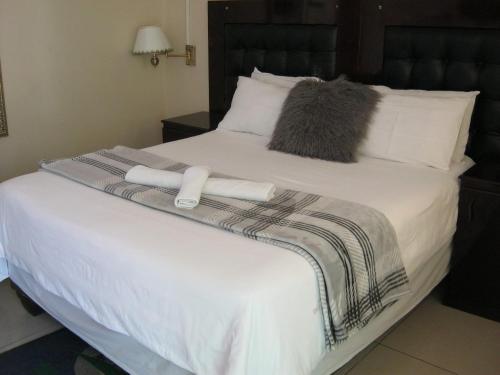 a large white bed with two towels on it at Mashamba Country House in Giyani