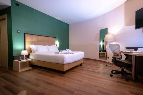a bedroom with a bed and a desk with a computer at UNA HOTELS MH Matera in Matera