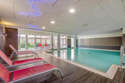 una piscina con sillas rojas en un edificio en Résidence Pierre & Vacances La Petite Venise en Colmar