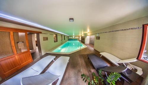 a swimming pool in a building with chairs around it at Borhotel Sziluett Farkasmály in Gyöngyös