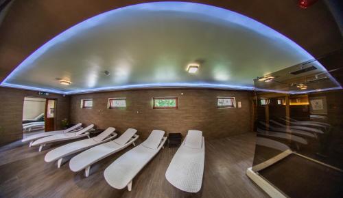 a group of white chairs in a room at Borhotel Sziluett Farkasmály in Gyöngyös