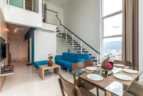 sala de estar con mesa de comedor y sofá azul en Maritime Luxury Suite By J&K Homestay, en George Town