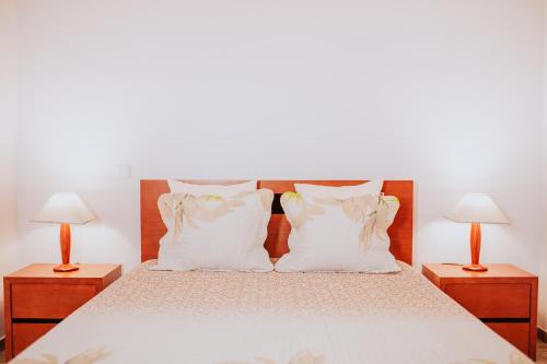 a bed with white pillows and two night stands at Casa da Morena by Amazing Madeira in Santa Cruz