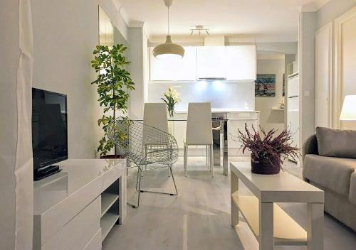 a living room and kitchen with a couch and a television at Stil Mar Anna Terra - by Apartamentos Stil Mar Anna in L'Escala