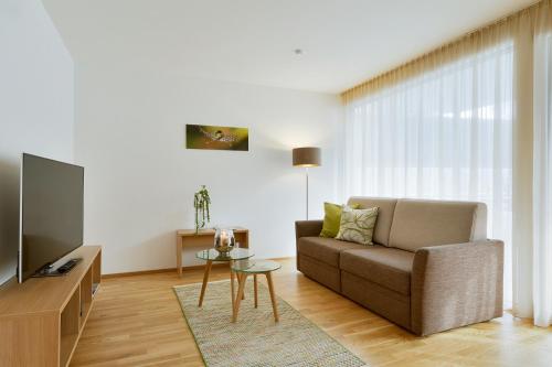 a living room with a couch and a tv at Relaxed Urban Living - Aparthotel und Boardinghouse in Dornbirn