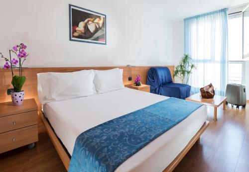 1 dormitorio con 1 cama grande y 1 silla azul en Aparthotel Esperya en Lignano Sabbiadoro