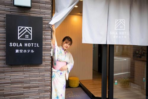 
a woman standing in front of a door with a sign at SOLA HOTEL in Tokyo
