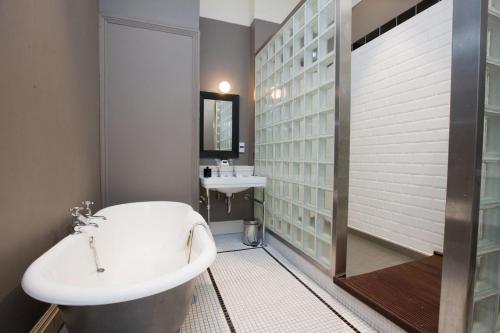 a bathroom with a white tub and a sink at Hotel du Vin Birmingham in Birmingham