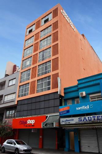 a tall building with a car parked in front of it at Hotel Express Confort in São Leopoldo