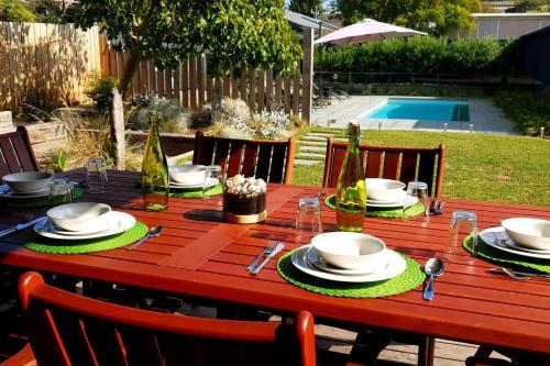 a wooden table with plates and glasses on it at Pool to Sand in 800mtrs - Heated Pool and Pet Friendly in Rye