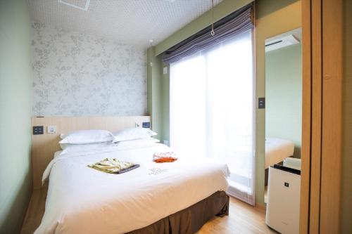 a bedroom with a bed with white sheets and a window at SOLA HOTEL in Tokyo