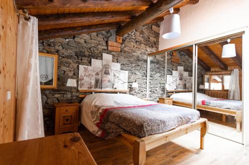 a bedroom with two beds and a stone wall at Les Balcons du Molliebon in Séez