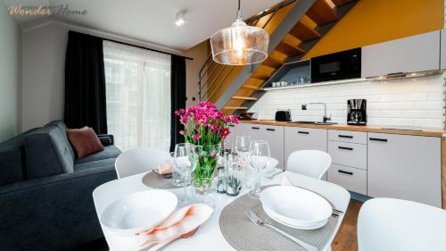 a dining room table with white chairs and flowers on it at Wonder Home - Apartamenty z widokami i blisko szlaków - w spokojnej części Karpacza in Karpacz