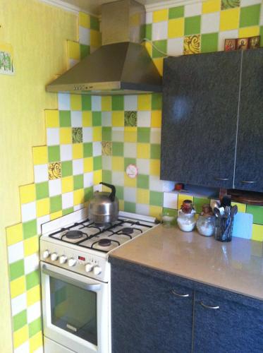 a kitchen with a stove with a tea pot on it at House with flowers in Zatoka