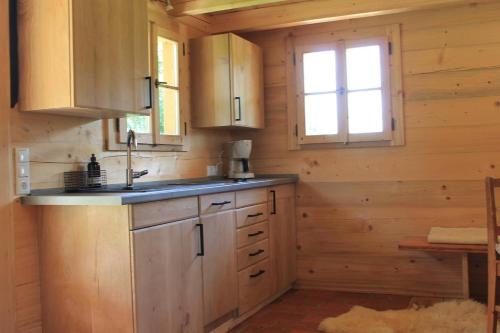 cocina con armarios de madera, fregadero y ventana en Holzchalet, en Kirchanschöring