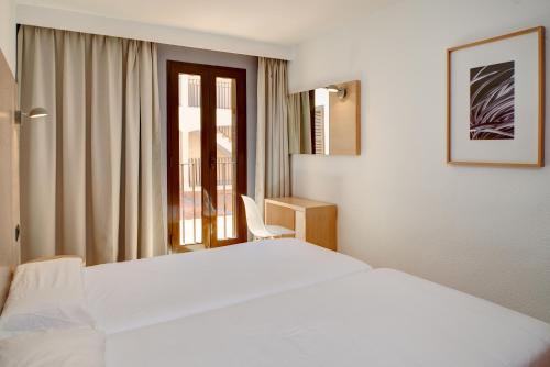 una camera d'albergo con un letto bianco e una finestra di Protur Floriana Resort 3* SUP a Cala Bona