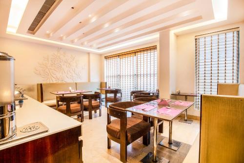 a dining room with tables and chairs and windows at Jasmine Boutique Hotel Jasola in New Delhi