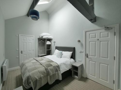 a white bedroom with a bed and a door at The Royal Hotel and Bar in Lancaster