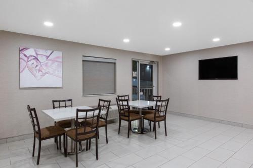 a dining room with tables and chairs and a flat screen tv at La Quinta by Wyndham Blue Springs in Blue Springs