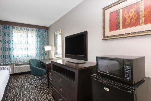a hotel room with a tv and a desk with a computer at La Quinta by Wyndham Blue Springs in Blue Springs