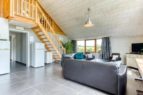 a living room with a couch and a staircase at Château Ferme de Laval in Sainte-Ode