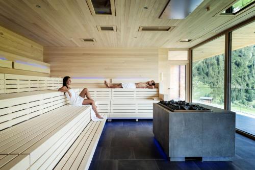a woman sitting in a sauna with a man sleeping at Wellnesshotel Warther Hof in Warth am Arlberg