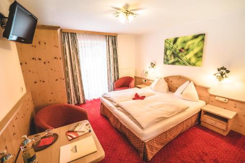 a hotel room with a bed and a television at Hotel Metzgerwirt in Kirchberg in Tirol