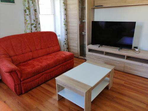 a living room with a red couch and a tv at Luise Wehrenfennig & Haus EvA in Bad Goisern