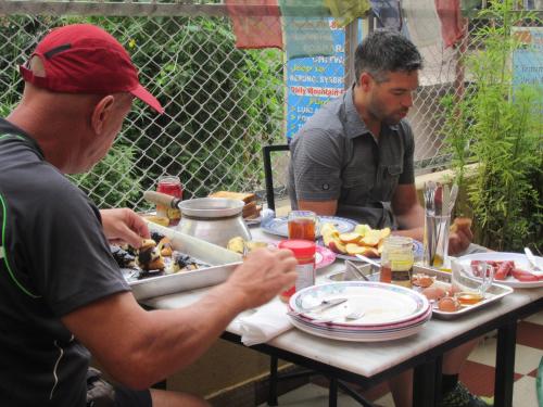 two men sitting at a table eating food at STUPA VIEW INN in Kathmandu