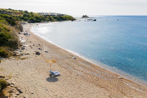 a beach with an umbrella and a chair at Villa Sea La Vie in Kiotari