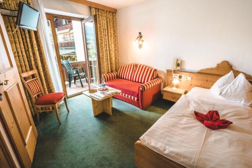 a hotel room with a bed and a couch at Hotel Metzgerwirt in Kirchberg in Tirol