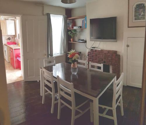 uma sala de jantar com uma mesa e cadeiras e uma televisão em Charming grade 2 listed house em Canterbury
