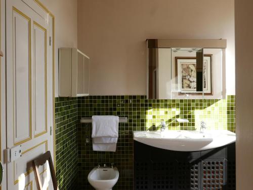 a green tiled bathroom with a sink and a mirror at La Buffonnerie in Moutiers-Saint-Jean
