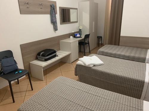 a hotel room with two beds and a table and chair at Hotel Siro in Milan