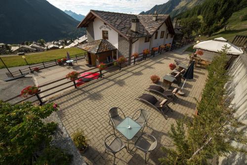 a patio with tables and chairs in front of a building at Hotel Le Clocher in Champoluc