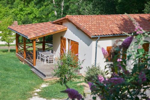 a small cottage with a deck and a table and chairs at Village de Montmarsis in Gourdon-en-quercy