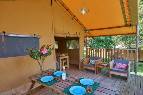 a patio with a table and chairs on a deck at Village de Montmarsis in Gourdon-en-quercy