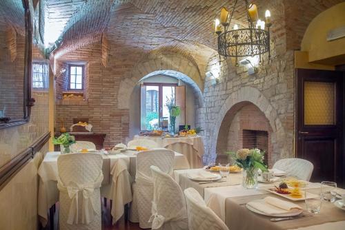 un comedor con mesas blancas y sillas blancas en hotel dei consoli en Gubbio