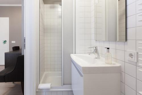 ein weißes Badezimmer mit einem Waschbecken und einer Badewanne in der Unterkunft Hotel Ódinsvé in Reykjavík