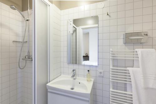a white bathroom with a sink and a mirror at Hotel Ódinsvé in Reykjavík