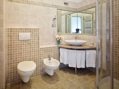 bagno con lavandino, servizi igienici e specchio di Albergo Garnì Villa Moretti a Riva del Garda